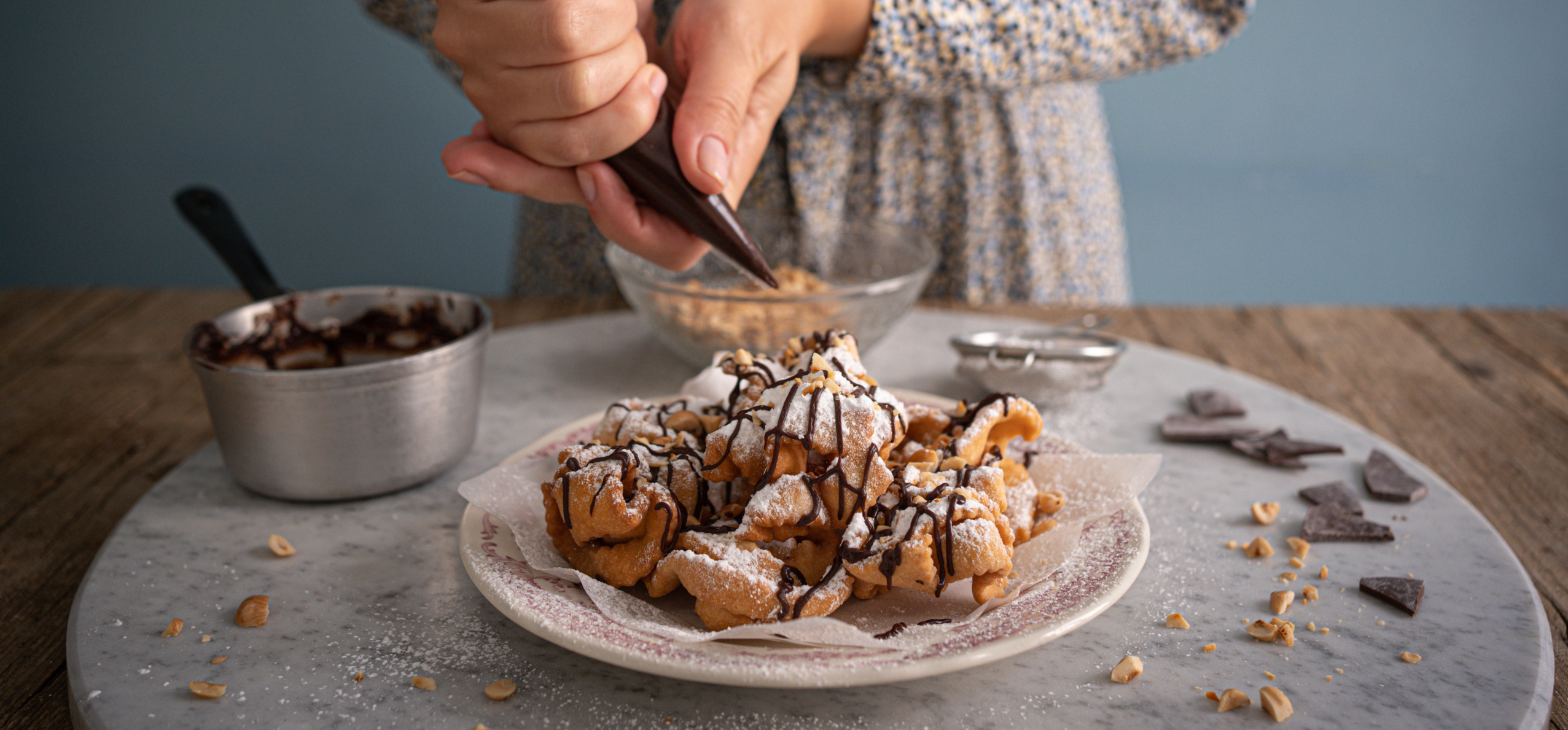 Fränkische Schneeballen con cioccolato fuso, zucchero a velo e granella di nocciole