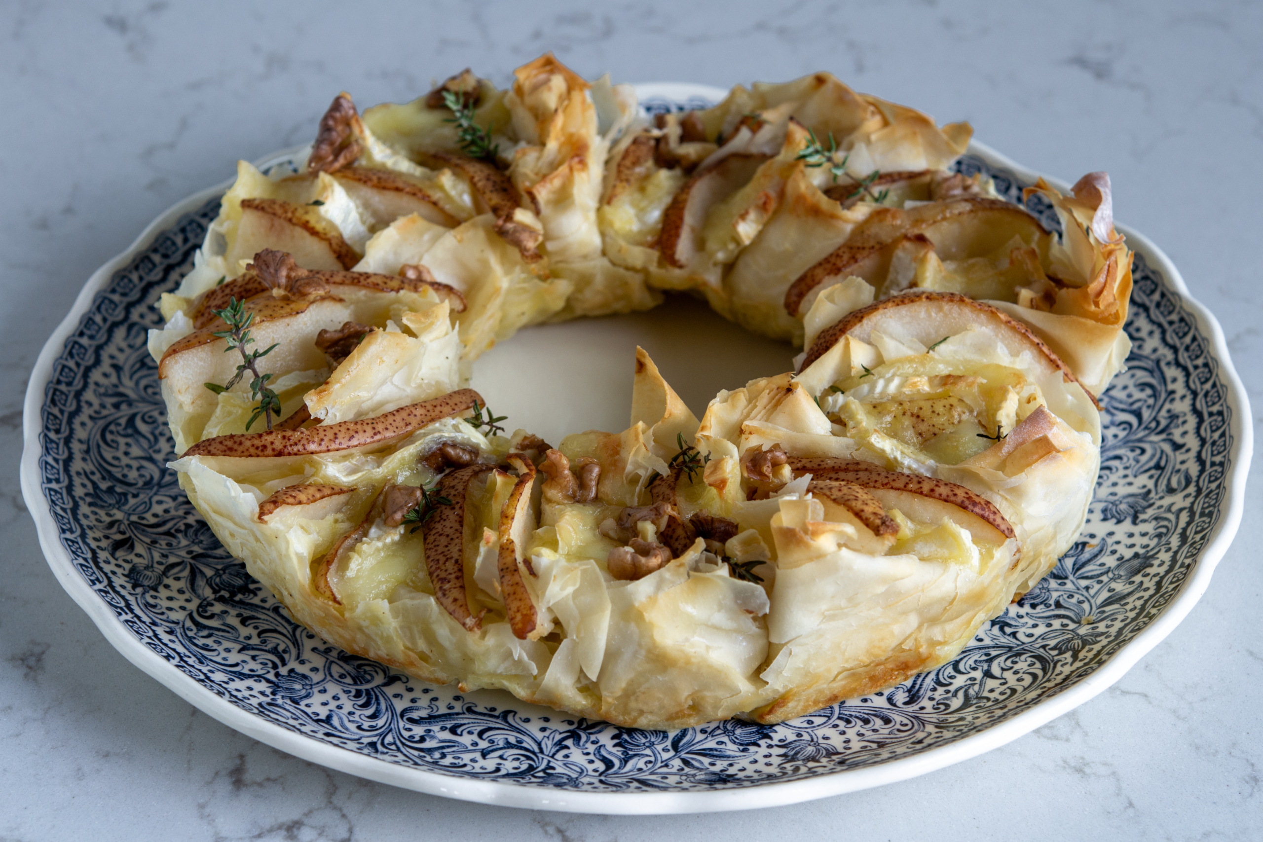 Torta fisarmonica con pasta phyllo a forma di ghirlanda con pere, noci, brie, timo, panna